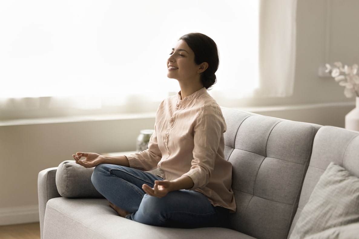 A young woman in meditative seating position on the couch