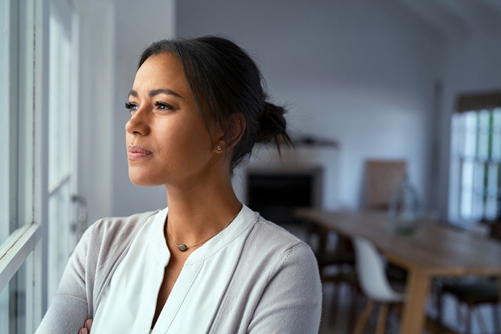 A woman looking concerned by a window